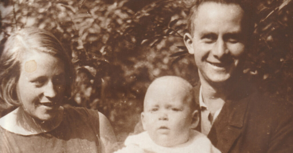 Familienfoto von 1931: links meine Oma Käthchen mit kinnlangem Bob und Seitenscheitel, sie blickt auf ein Baby, meinen Vater. Der proppere kleine Kerl wird von meinem Opa gehalten, der in die Kamera grinst. Der Kleidung nach zu urteilen ist es Sommer und mein Vater ca. 6 Monate alt.