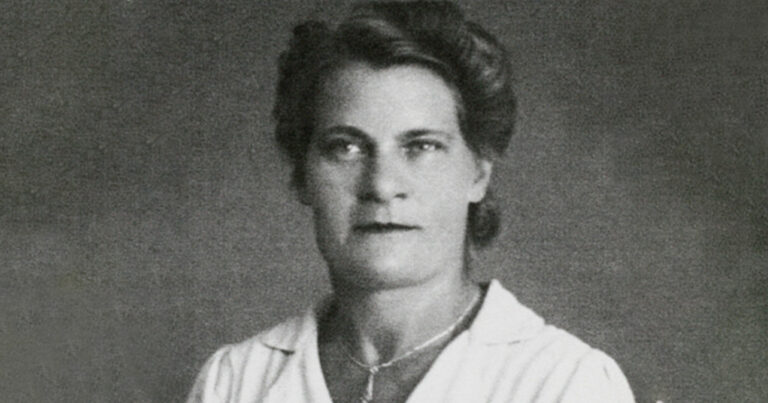 Schwarzweiß Portrait von Toos Verhagen aus den Anfang 30er Jahren. Sie trägt eine Hochsteckfrisur, Maskara, Lippenstift und eine weiße Bluse.